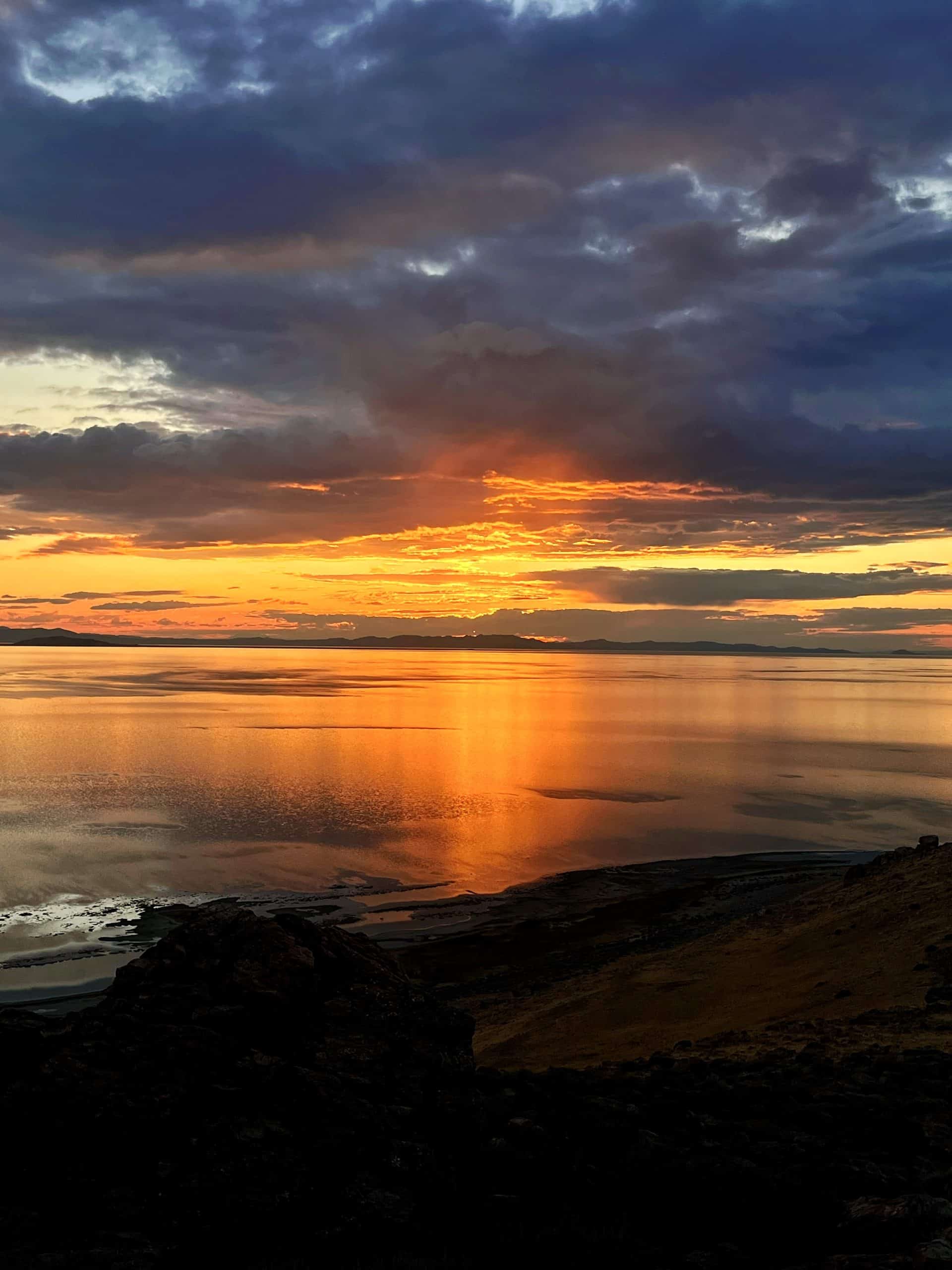 Calm water reflecting a dramatic sunset sky at Antelope Island State Park.