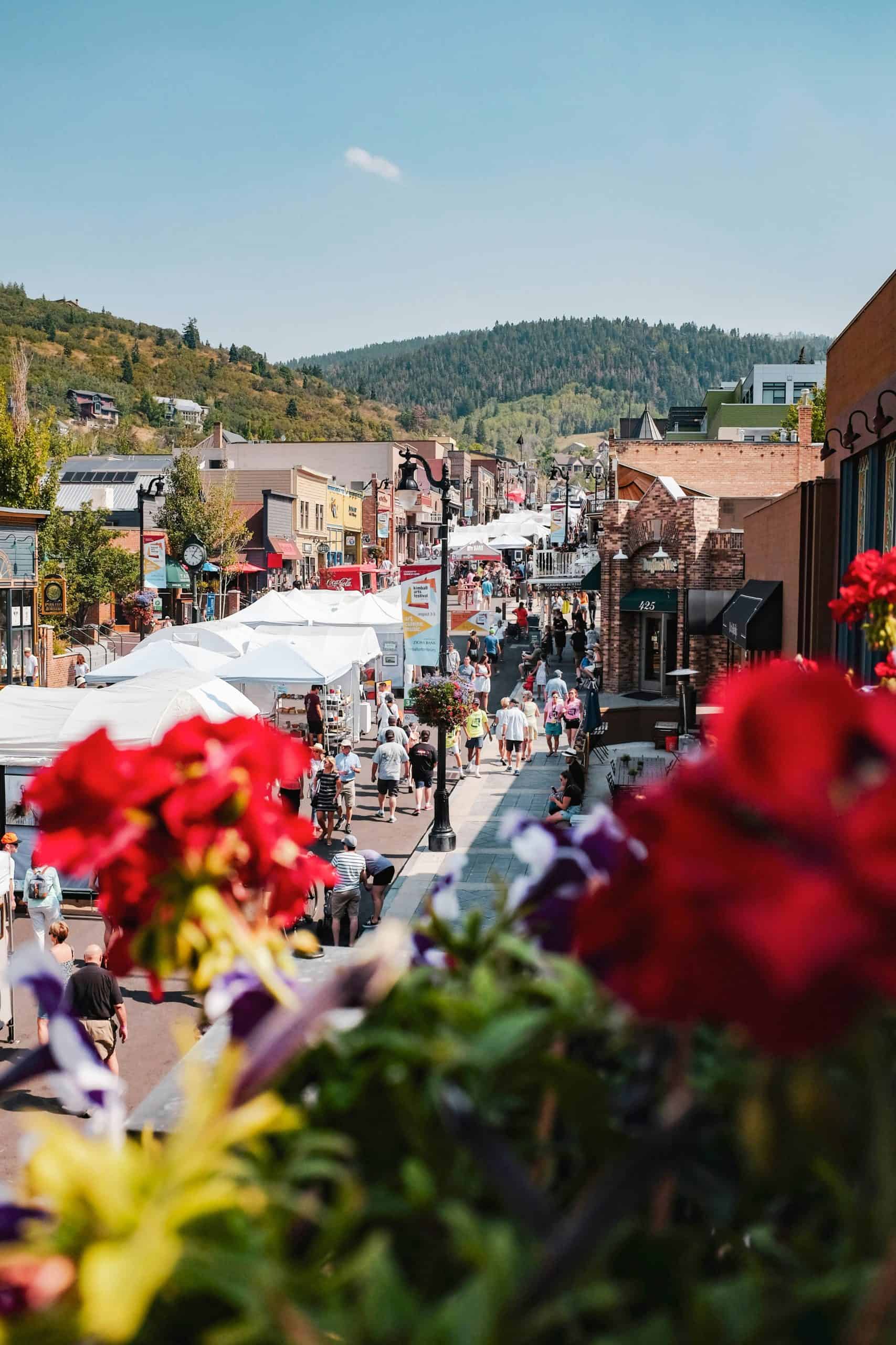 People walking Main Street in Park City in the background with out of focused flowers in the foreground. 