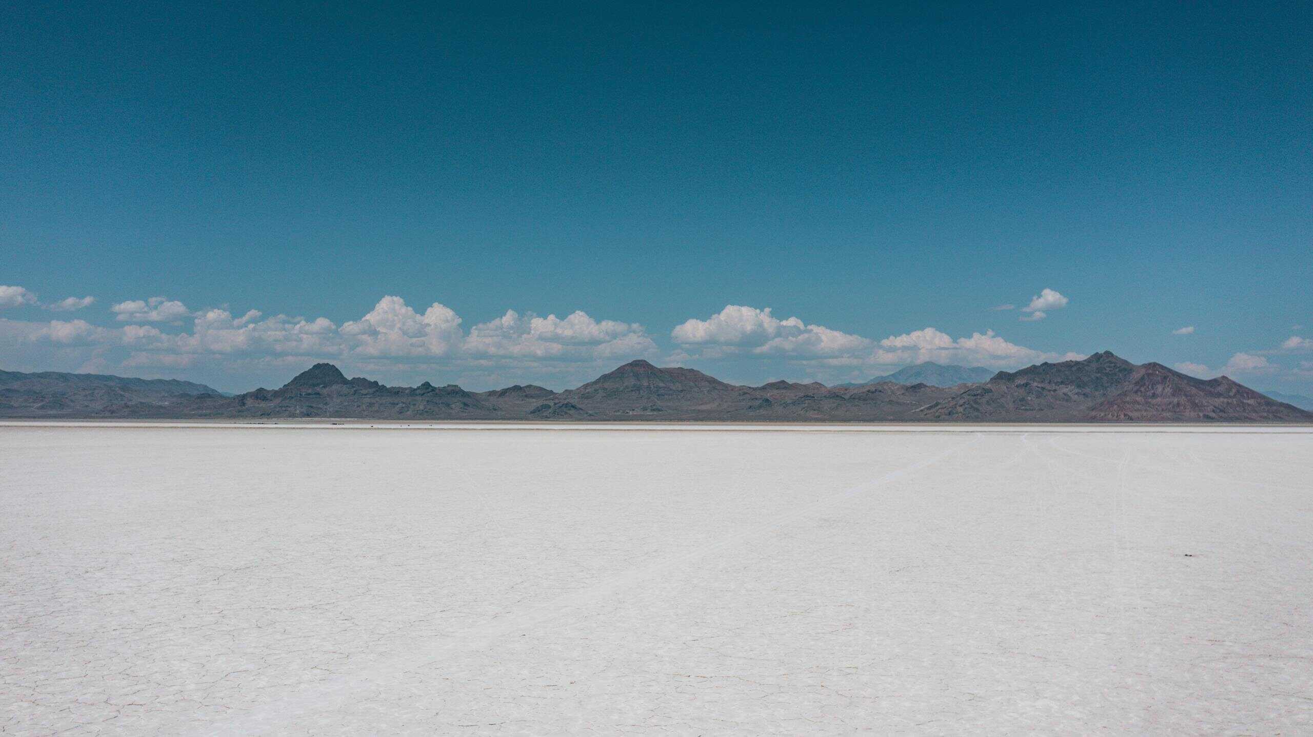 Expansive desert landscape with distant mountains under a clear blue sky.