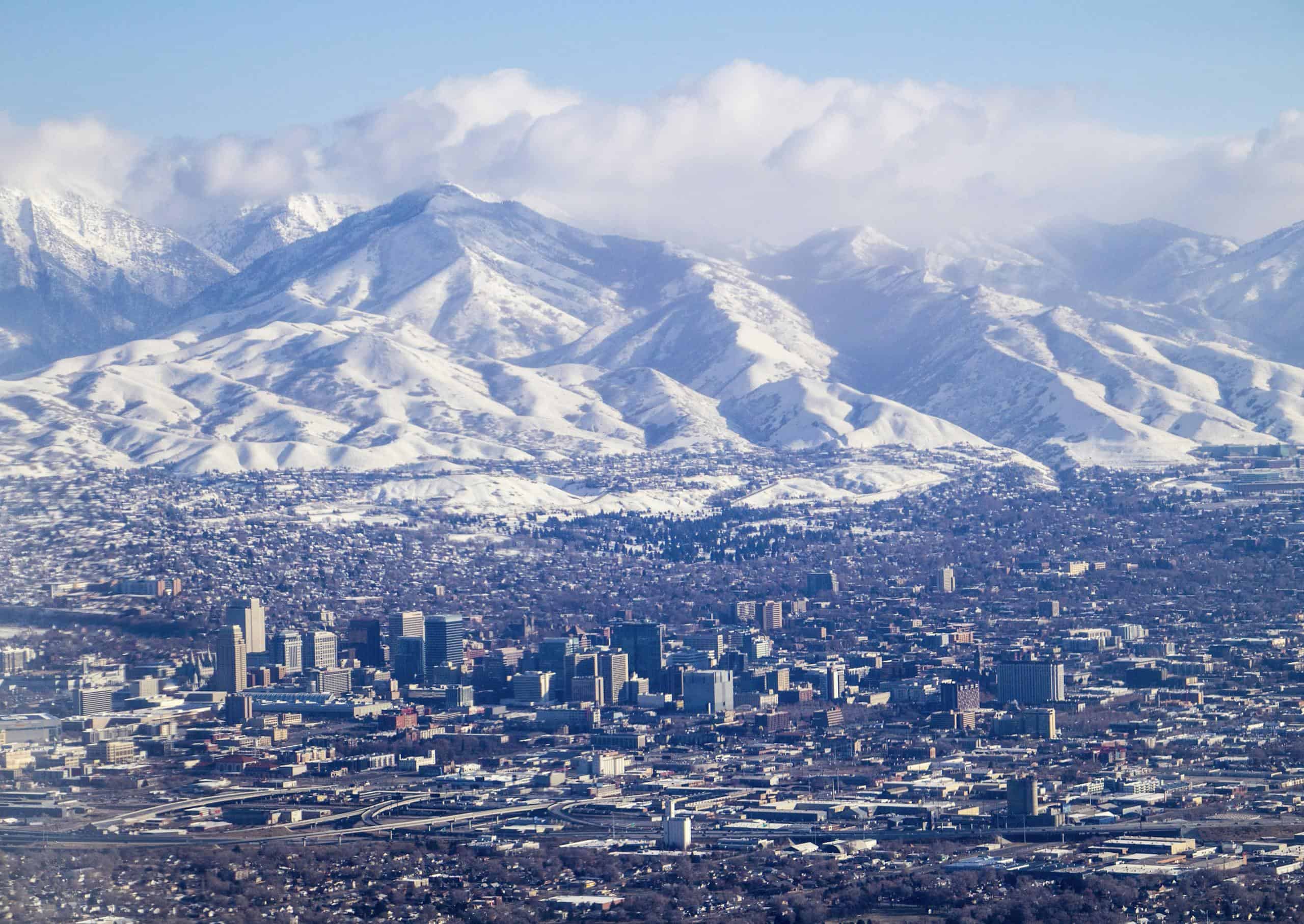 Stunning aerial view of Salt Lake City with the snow-covered Wasatch Range in winter, captured in clear daylight.
