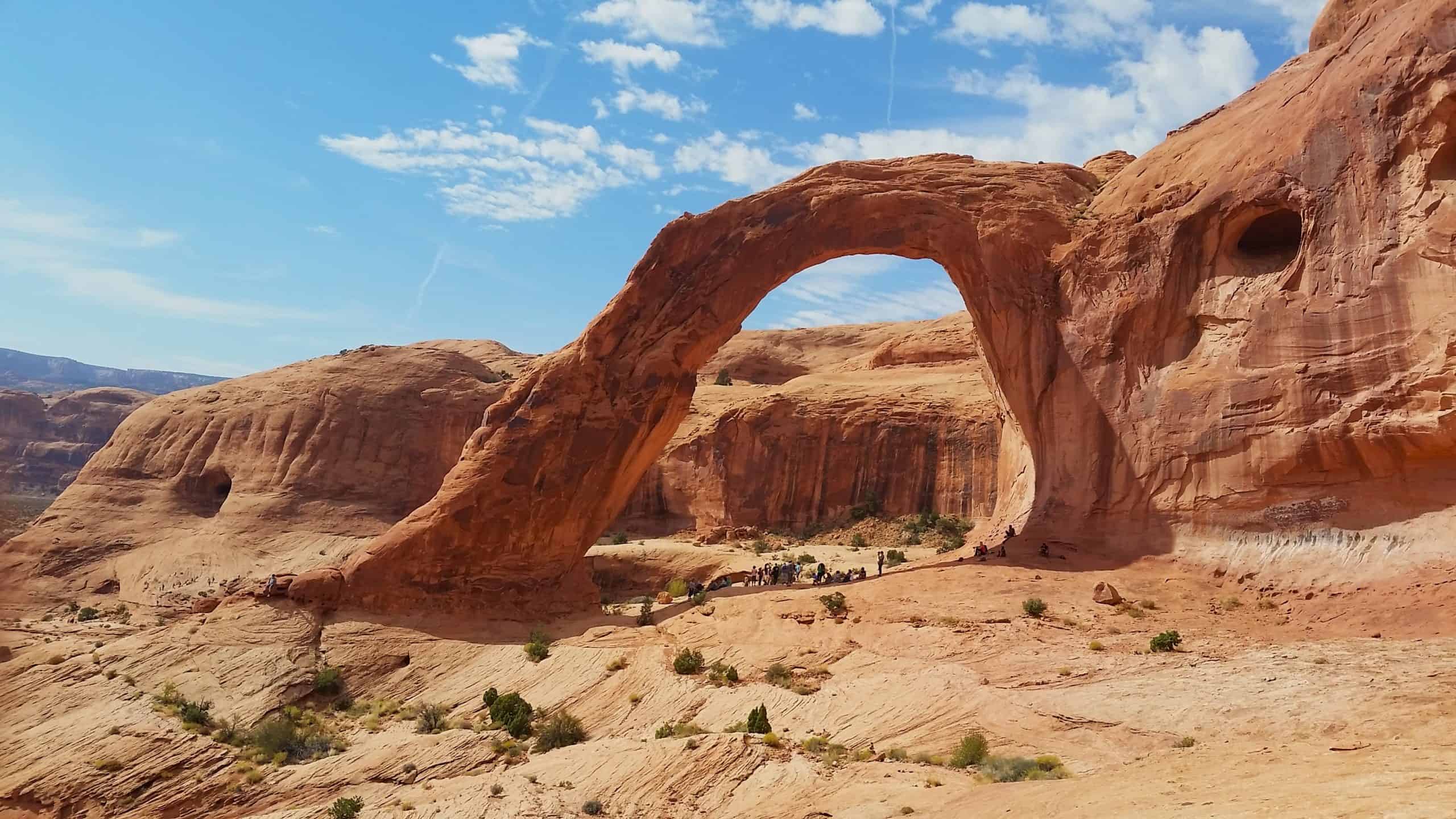 Massive Arch in the center of the photo, surrounded by red rock and blue skies near Moab, Utah. 