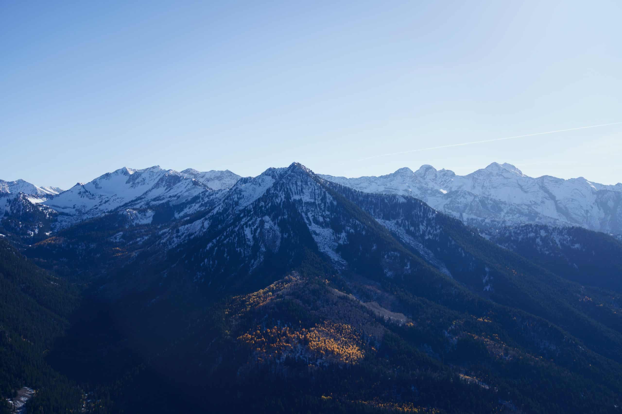 Moody lighting on snowy peaks and distant fall colors as viewed from Reynolds Peak in Big Cottonwood Canyon