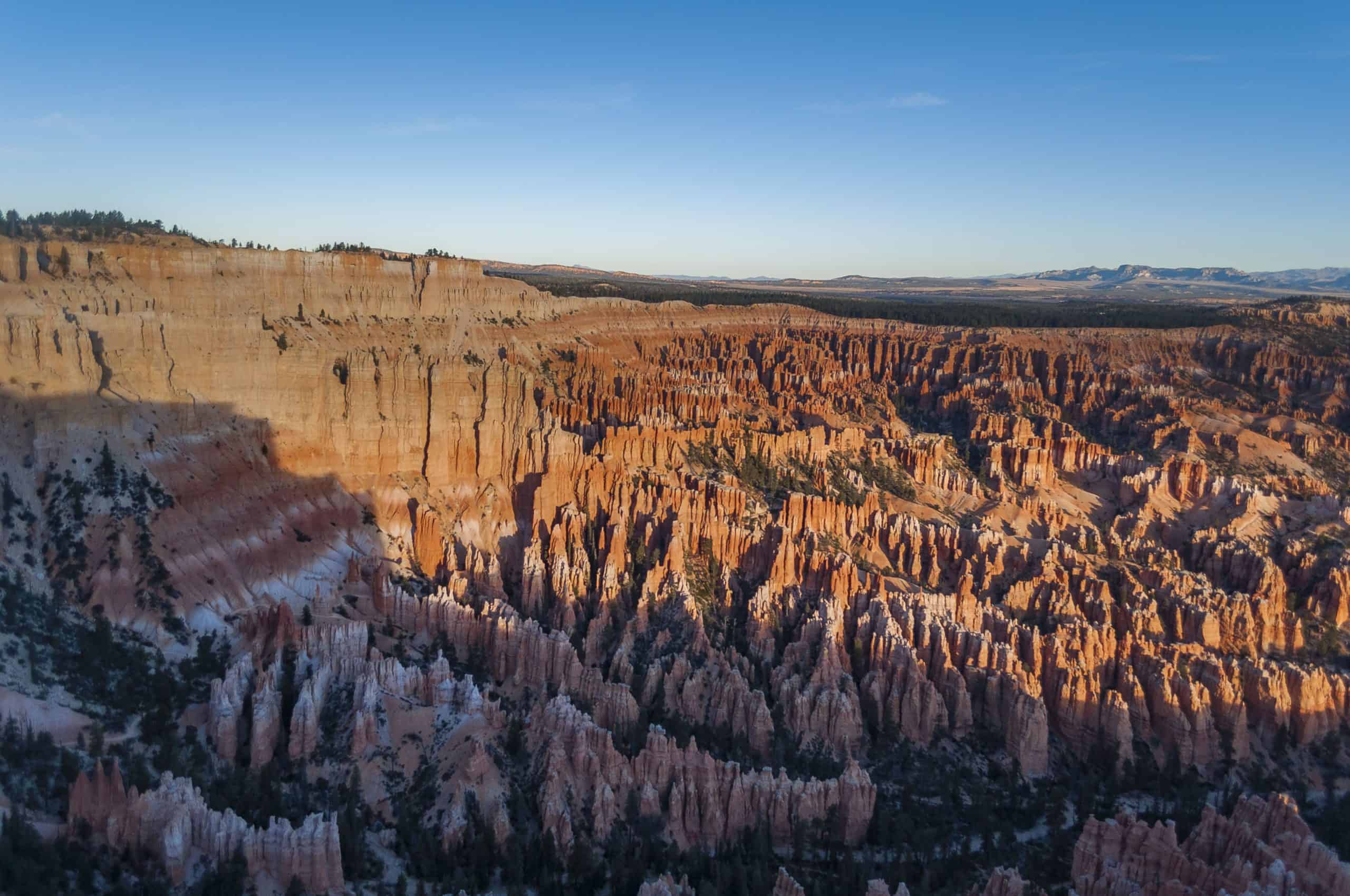 Vast views of endless hoodoos at Bryce Canyon National Park at sunrise with blue skies in the background. 