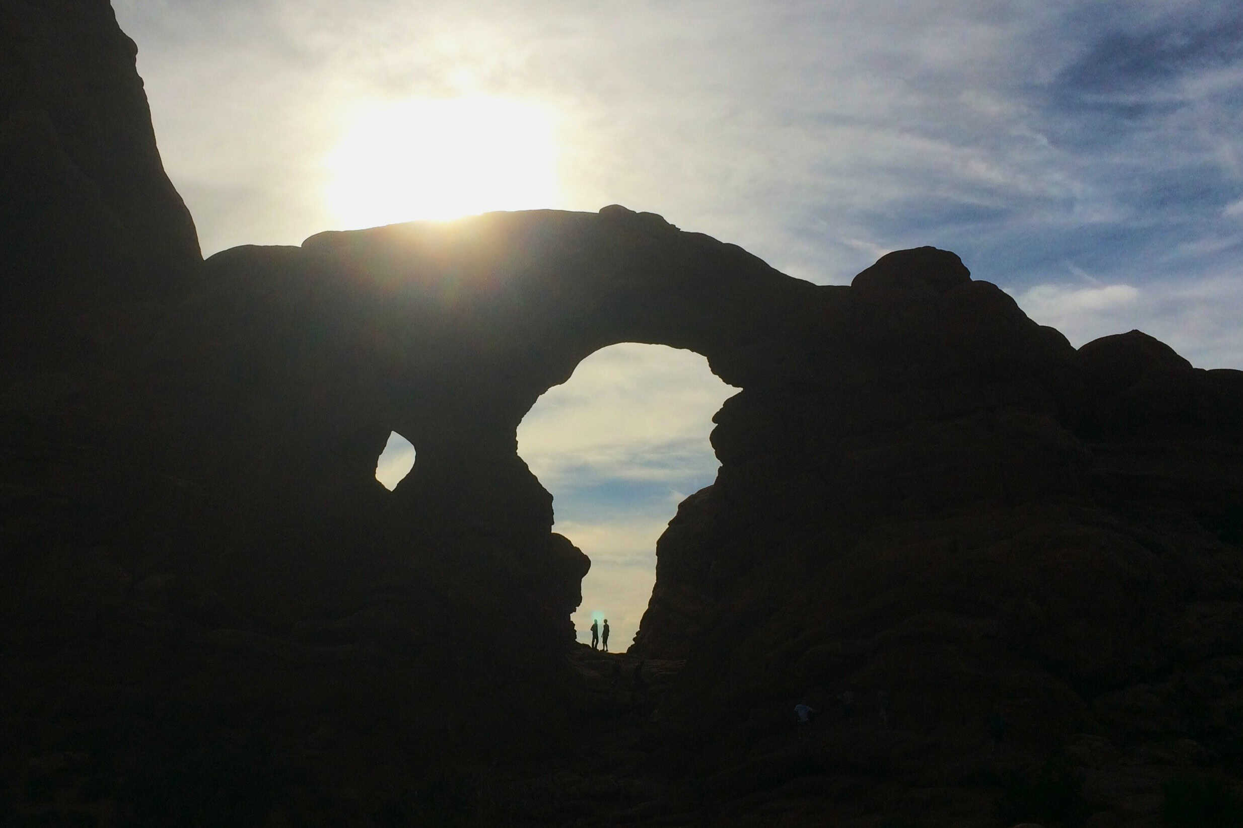 Silhouette of Turret Arch near sunset with sunlight shining through the opening in Arches National Park.