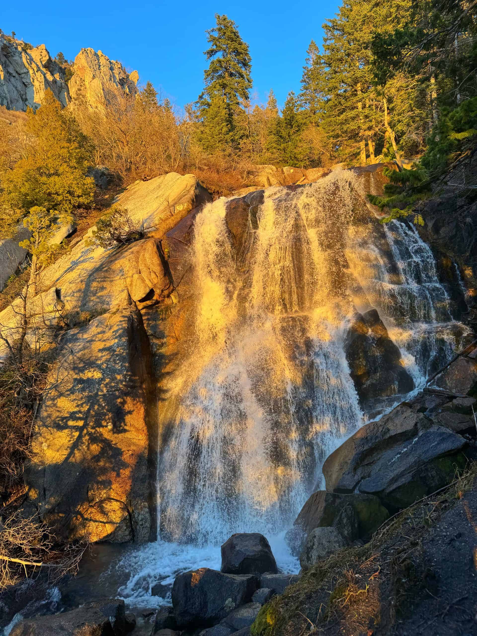 Water cascading over sunlit rock at Bells Canyon Lower Falls surrounded by white granite rock