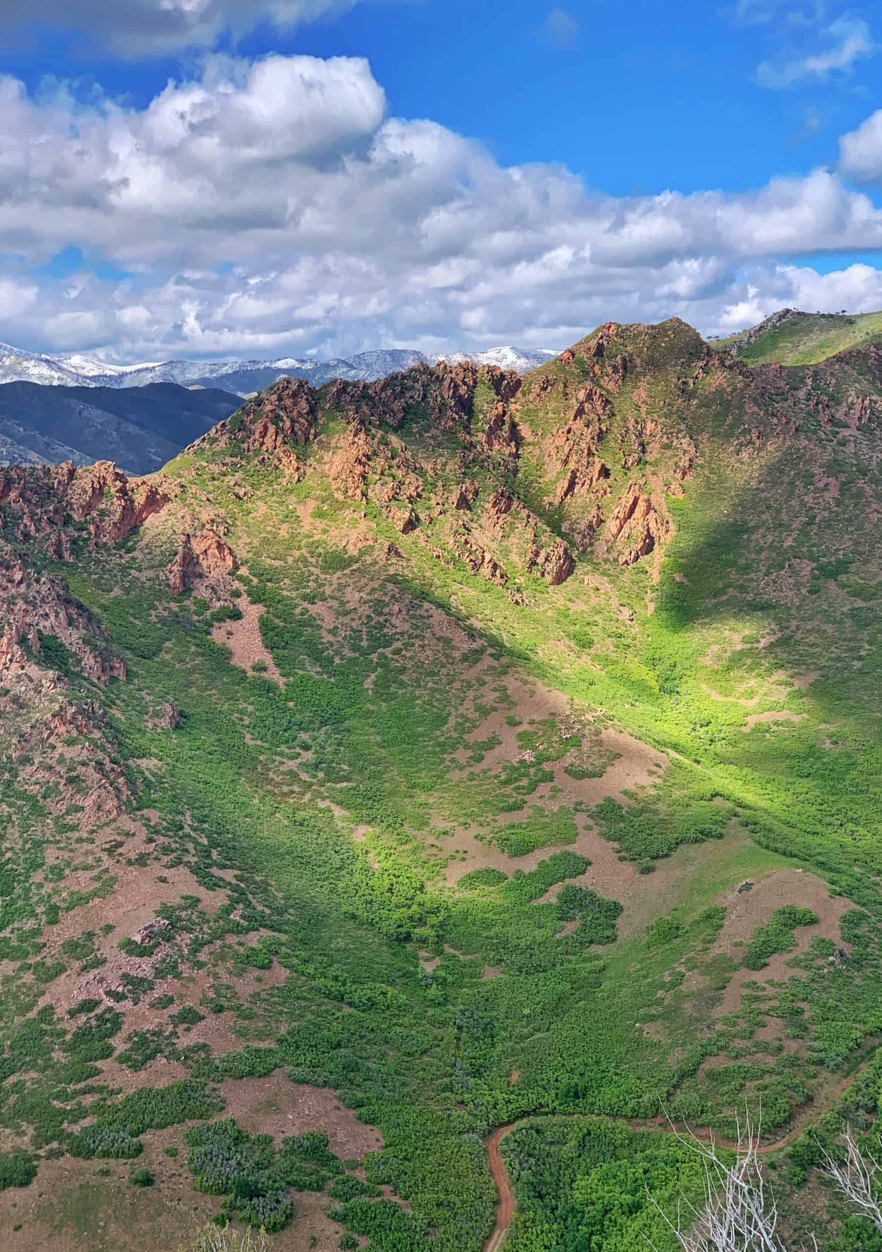 Filtered sunshine view near Salt Lake City of rugged mountain above green hill side