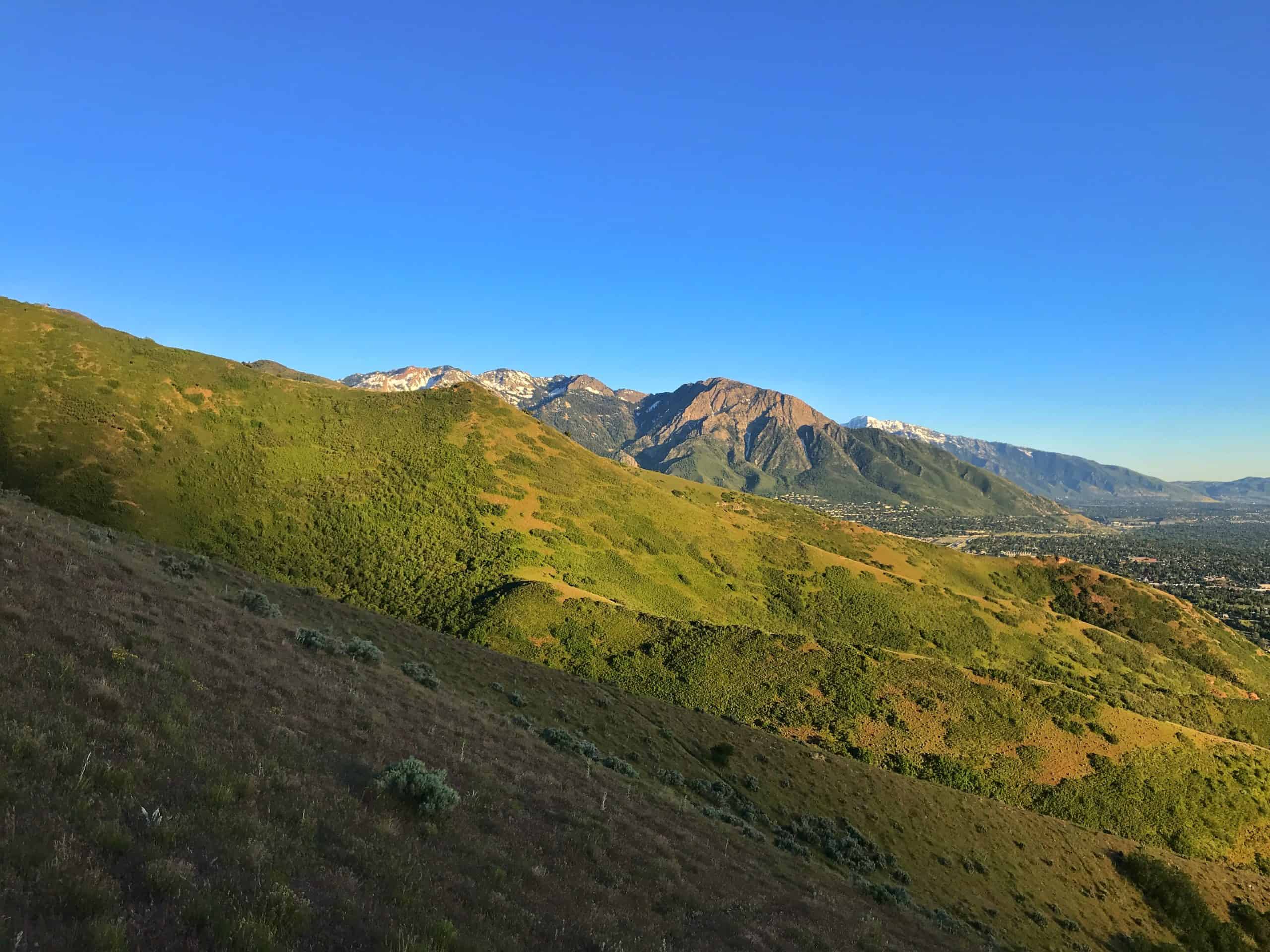 Golden Hour view near Salt Lake City of dramatic mountains in the background, and green hills in the foreground