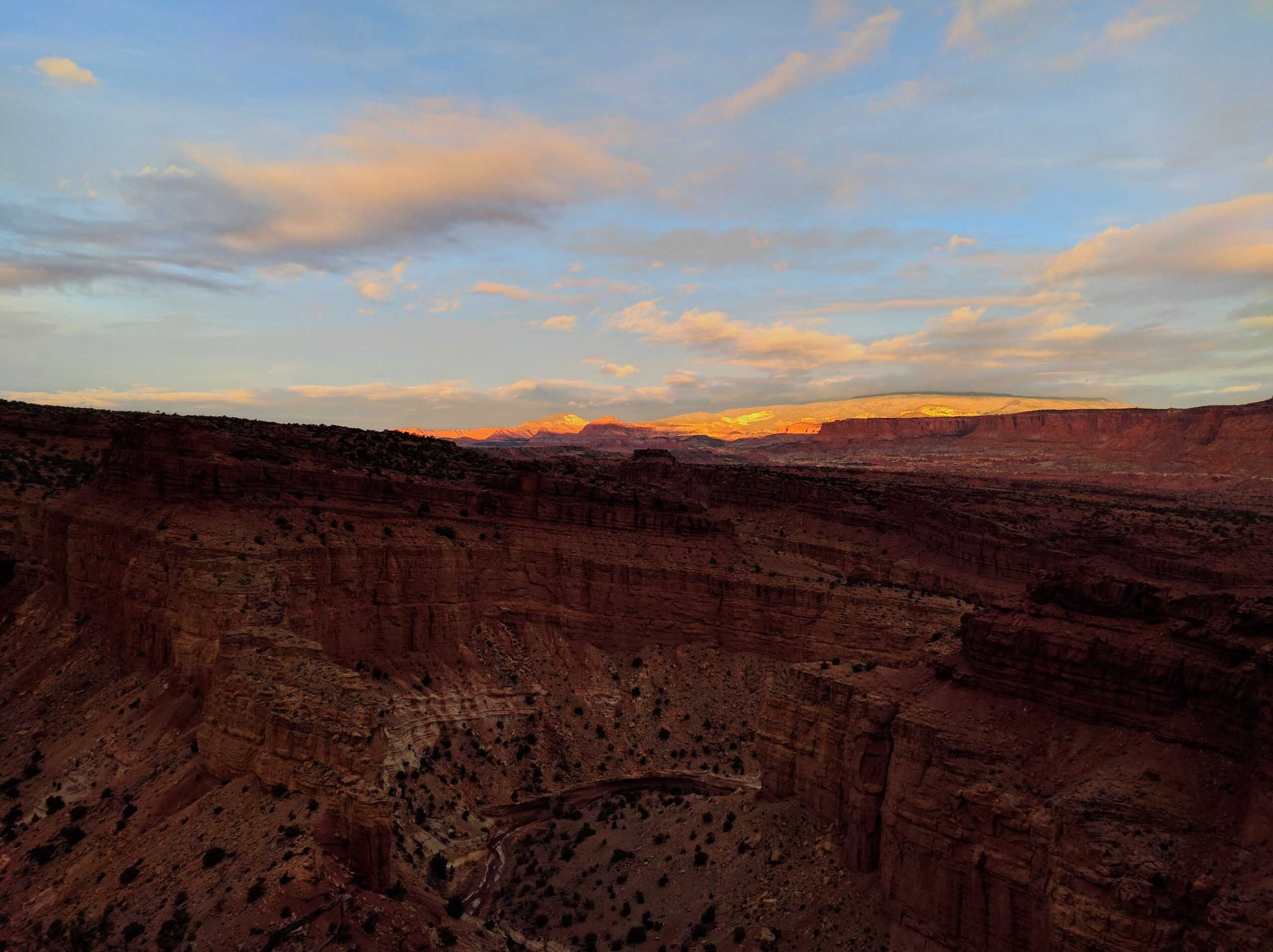 Deep canyon with distant mountains in golden hour lighting in Capitol Reef National Park, Utah.