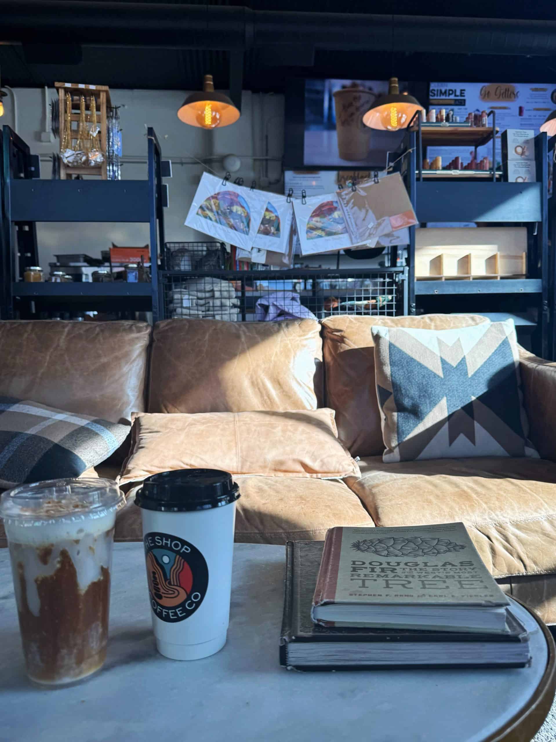 A cozy corner at a coffee shop in Orderville, Utah, featuring a leather couch, warm lighting, and two drinks. 

