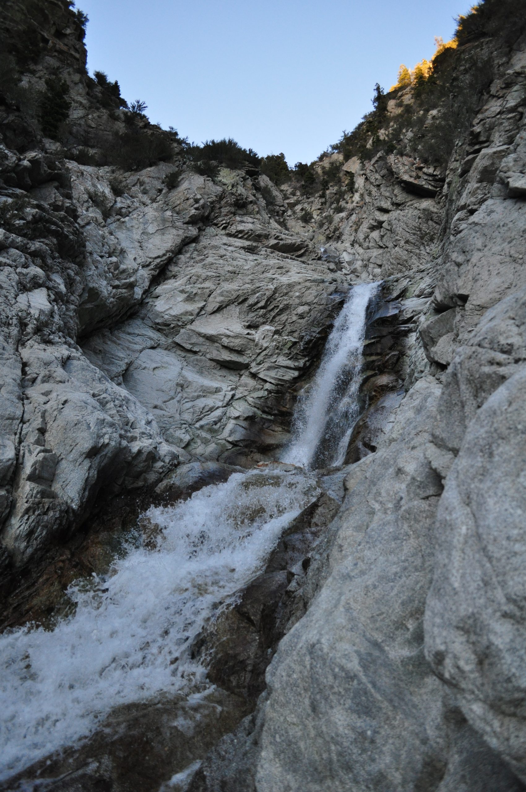 A close-up view of a waterfall cascading over rugged granite rocks, a popular hike in Little Cottonwood Canyon. 