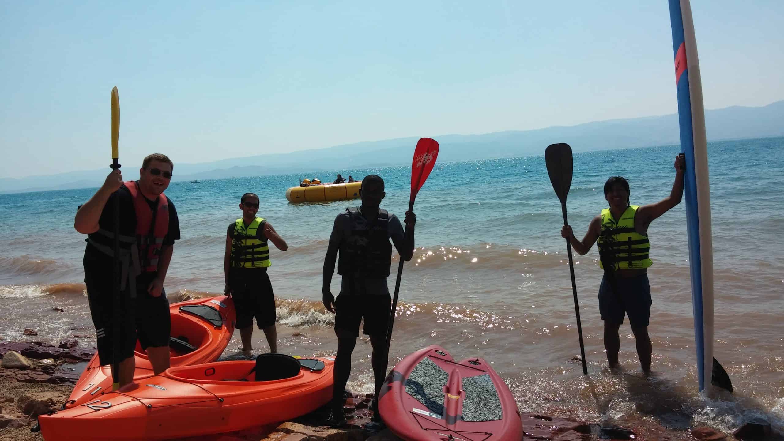 A Group of friends preparing to kayak at Bear Lake, wearing life jackets and holding paddles: experiencing one of the fun things to do at Bear Lake, Utah.