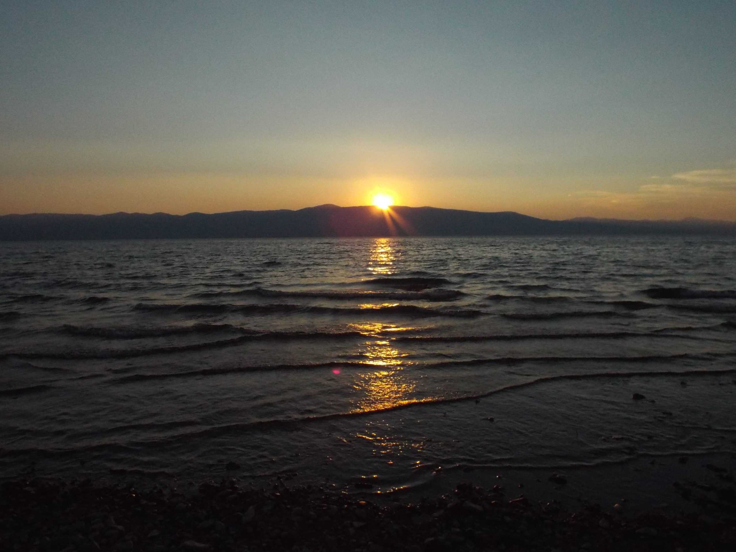 A serene sunset over Bear Lake from the East shore, with golden light reflecting on the water
