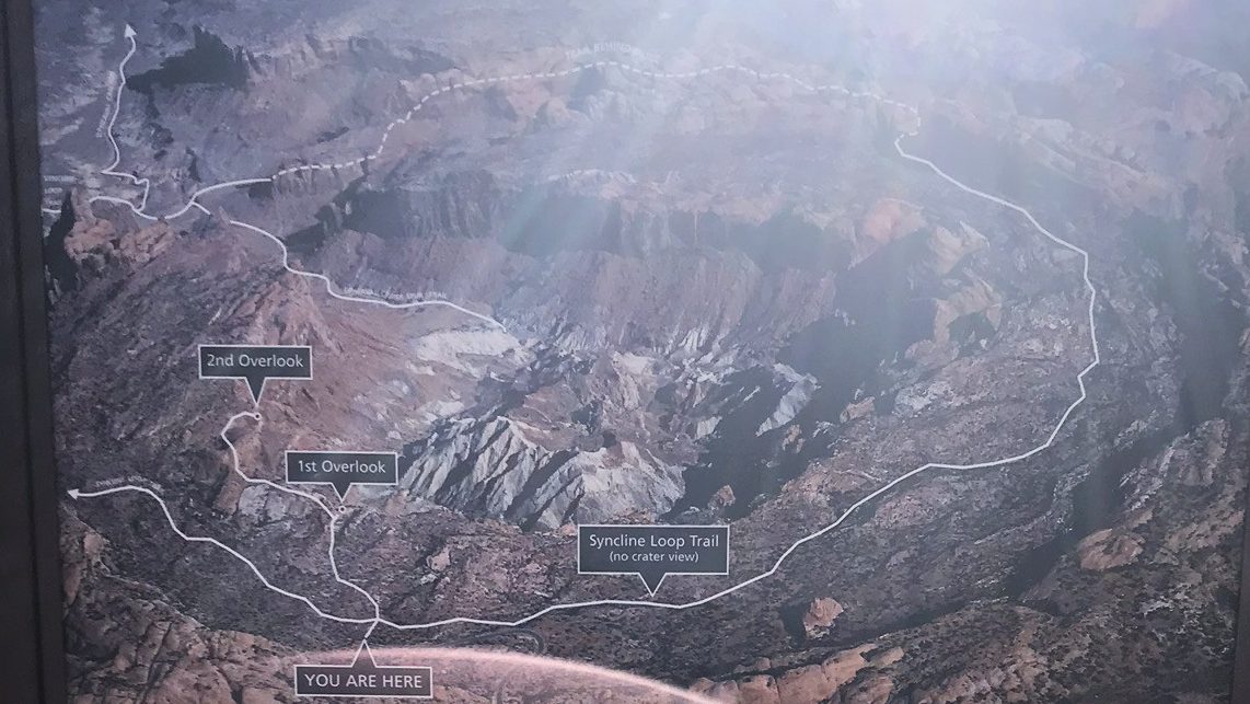Am outdoor trail map with overlook labels overlaid on a top-down view of layered canyon terrain, providing clear navigation details for hiking in the Upheaval Dome and Syncline Loop Trails