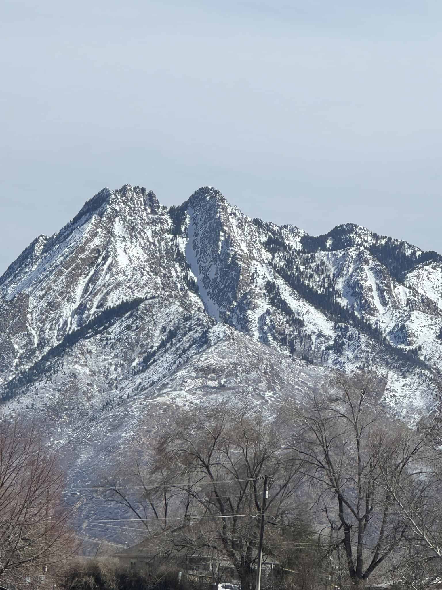 A dramatic, jagged and snowcapped, Mount Olympus, with it two peaks rises above Murray City in Utah
