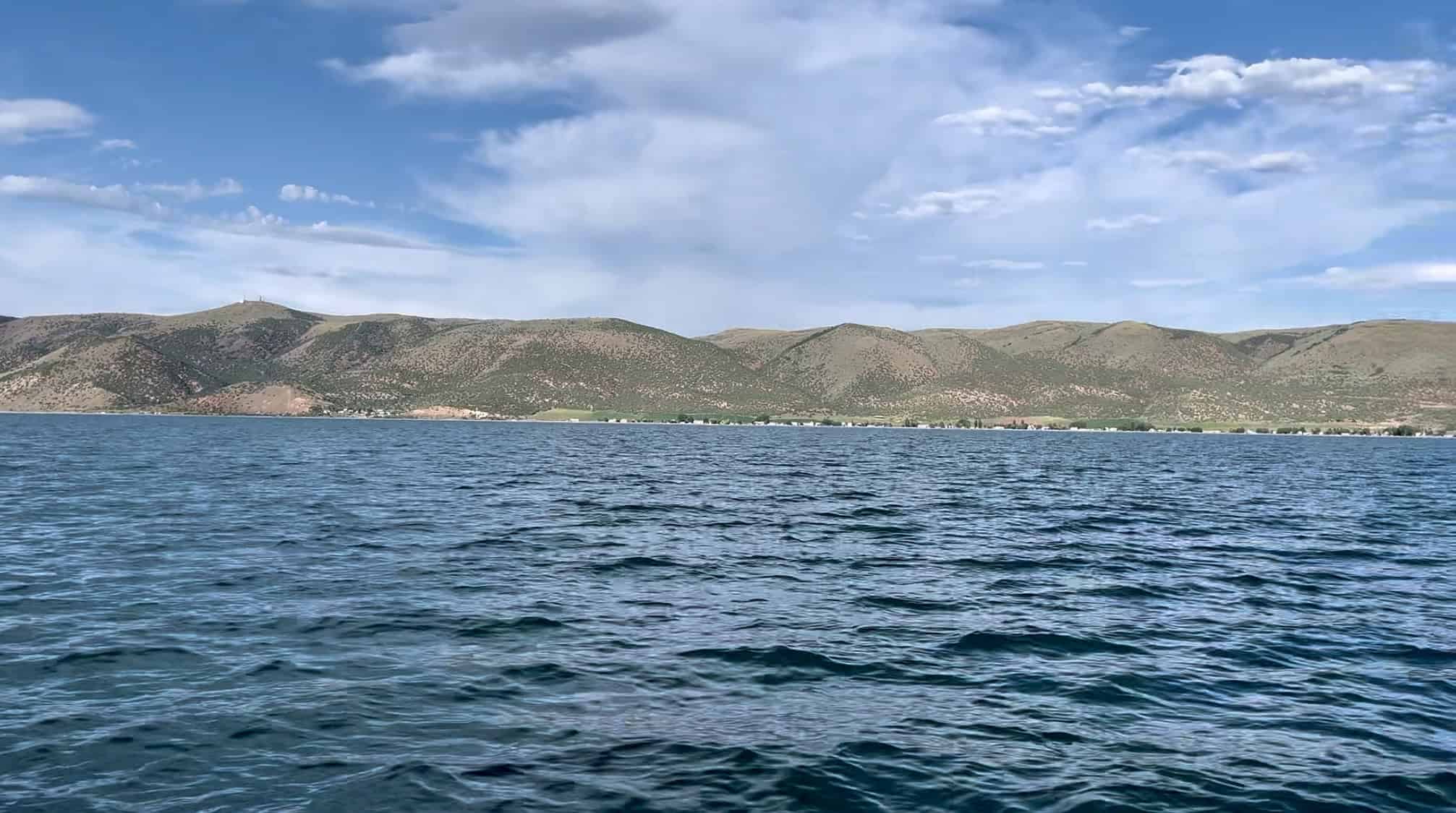 An open view from the middle of Bear Lakes, it's deep blue water set against desert hill sides under partially cloudy skies. 
