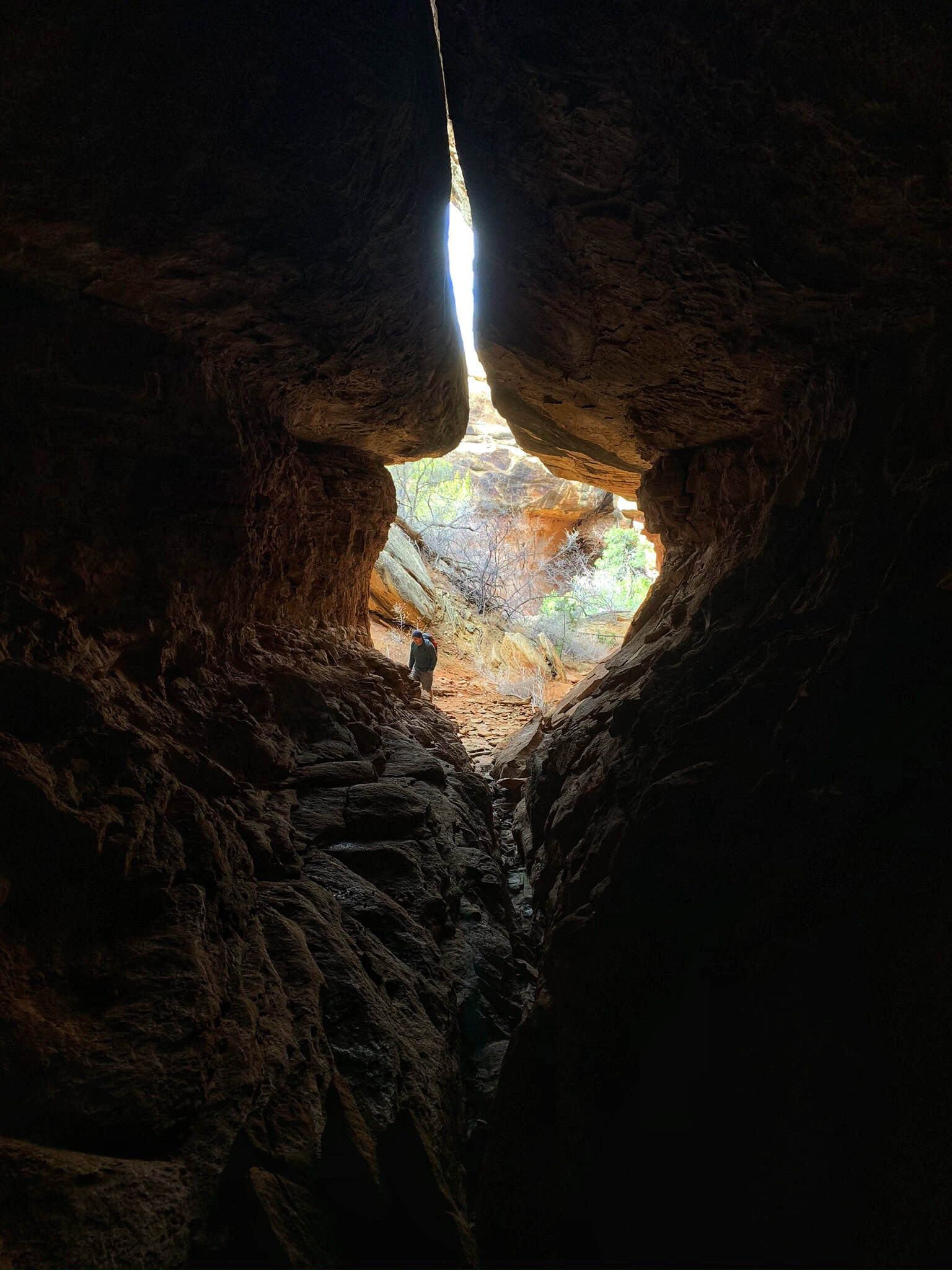 Peering through this dark crevice toward a sunlit opening captures the rewarding scenery you’ll discover while hiking in Canyonlands National Park.