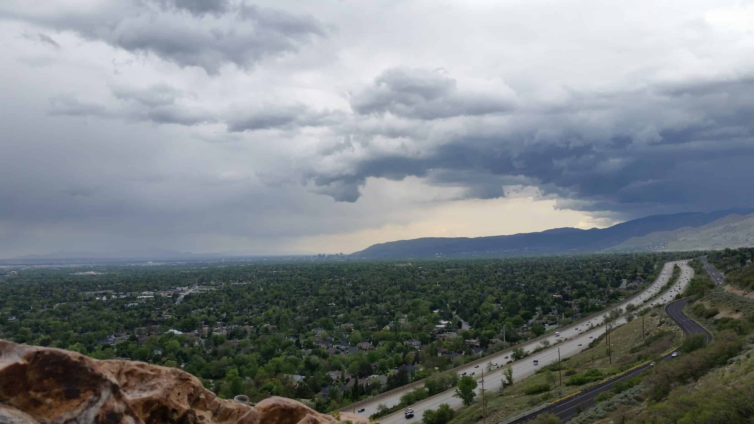 Dramatic storm clouds sweep over Salt Lake City from a high rocky vantage point on the hike to Mount Olympus, Utah.