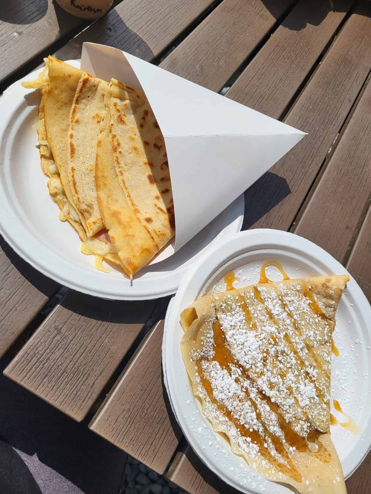 Two crepes sit on paper plates on a wooden table at Crepes and Coffee in Garden City, Utah