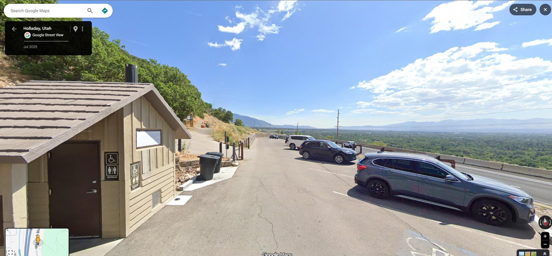 A paved parking lot with cars and small wooden comfort station  under a mostly blue sky, marking the starting point to Hike Mount Olympus, Utah.