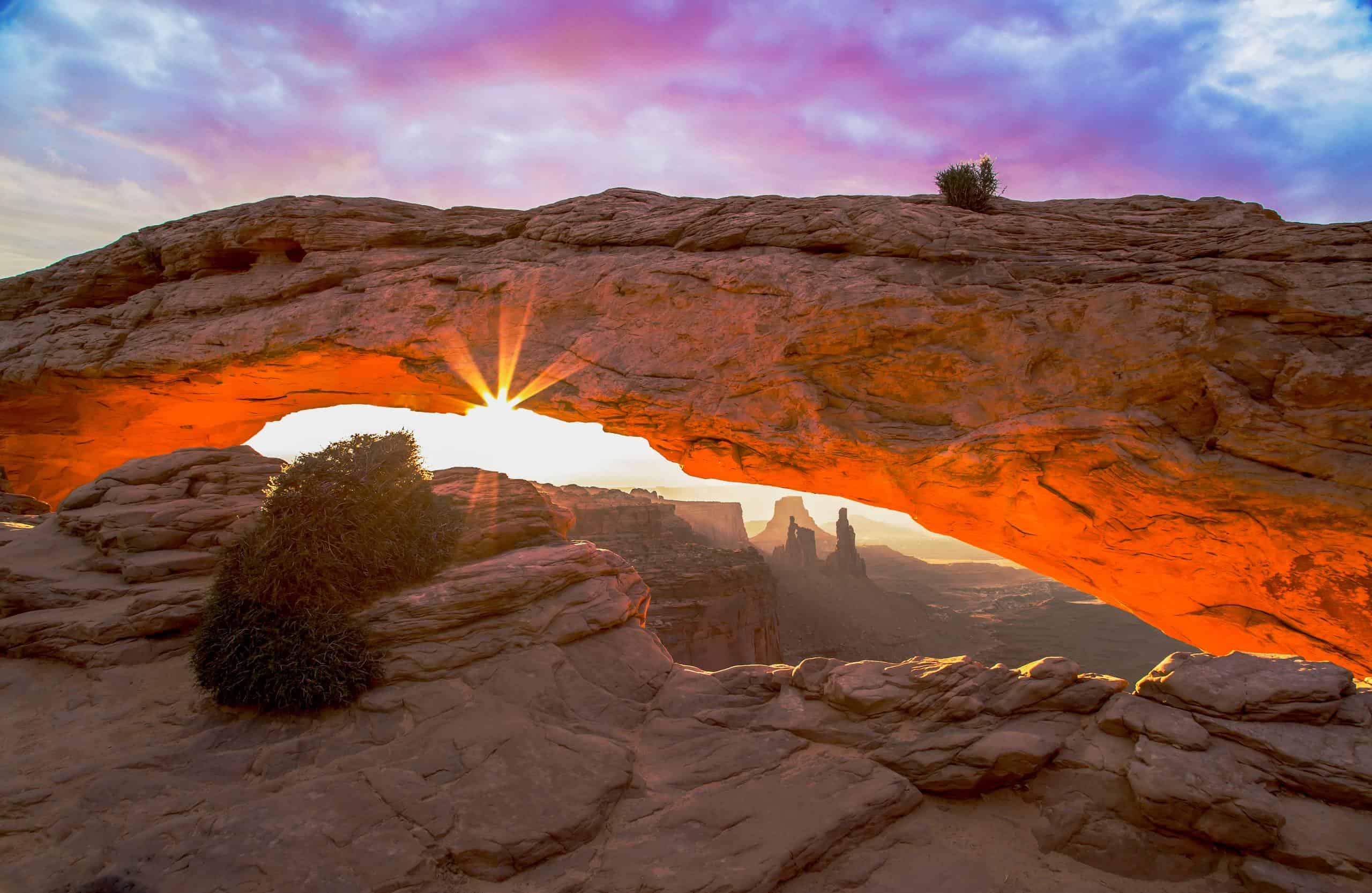 Majestic sunrise through Mesa Arch in Canyonlands National Park, Utah, illuminating the desert landscape.