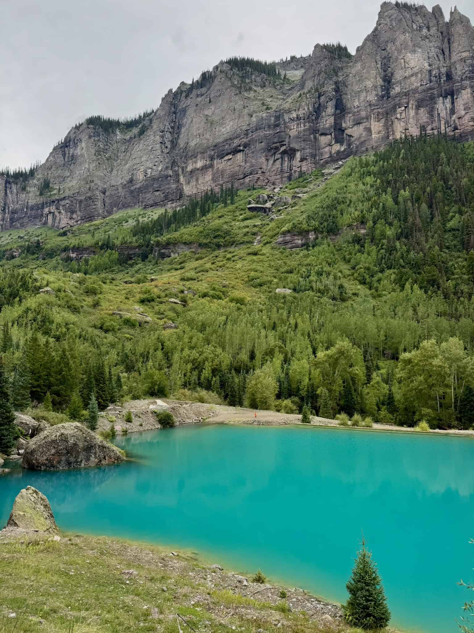 A vibrant turquoise pond nestles at the foot of imposing cliffs near Telluride, Colorado

