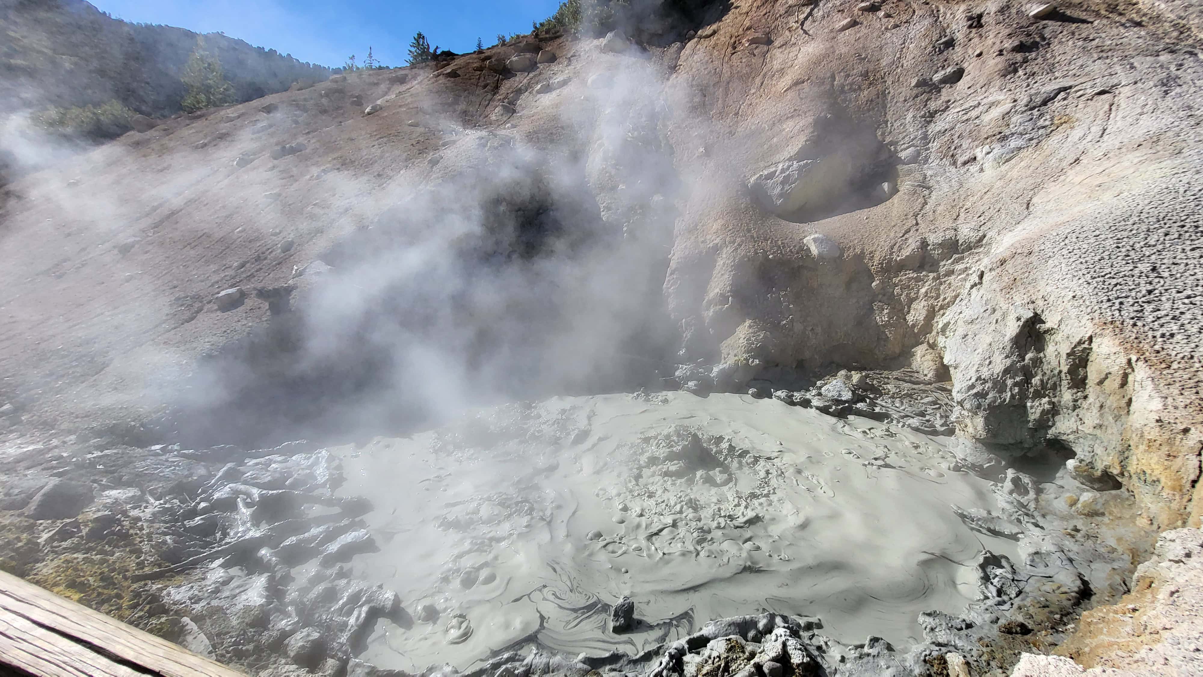 Bubbling mud pot and steam vents at Sulphur Works, surrounded by volcanic rock in Lassen Volcanic National Park.