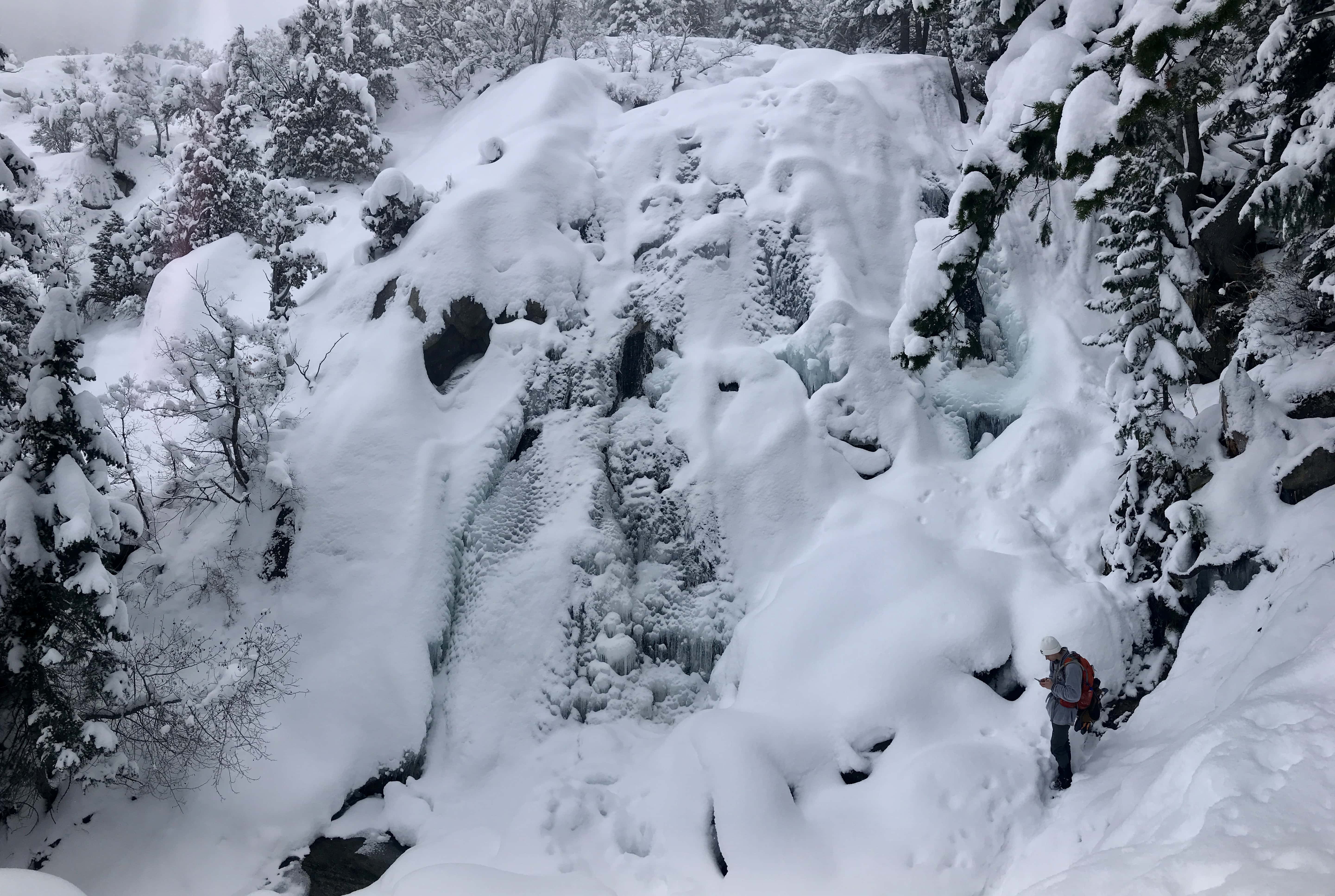 A close-up view of a frozen waterfall in Bells Canyon, completely frozen and covered in thick layers of snow and ice.
